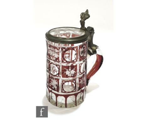 A 19th Century Bohemian beer stein in clear crystal with ruby flash decoration in a panel design with alternate foliate and p