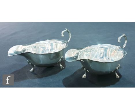 A pair of hallmarked silver sauce boats each raised on three stepped pad feet, Birmingham 1936, with thirteen low grade teasp