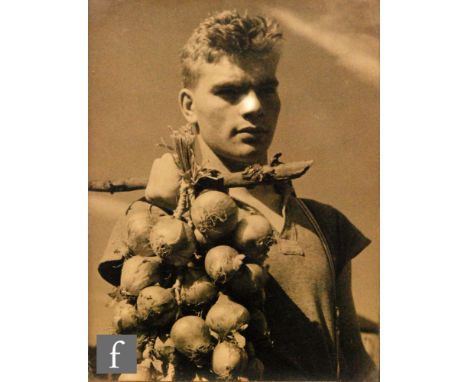 MONTAGUE GLOVER (1898-1983) - Portrait of Ralph carrying a string of onions, monochrome photograph, framed, 24cm x 18cm, also