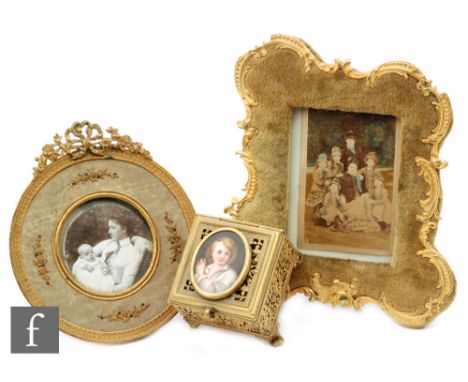 An early 20th Century gilt edge easel photograph frame with bow mount, a similar velvet cartouche shaped edge frame and a sma