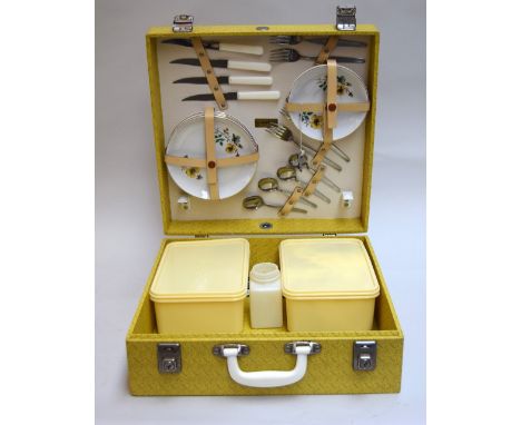 A vintage yellow Brexton picnic hamper with accessories for four people, comprising plates, saucers, flatware, teacups and co