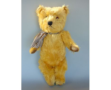 A 1950s teddy bear, 14" tall, possibly Chiltern Hugmee, with jointed head and limbs, stitched nose and mouth, amber eyes and 