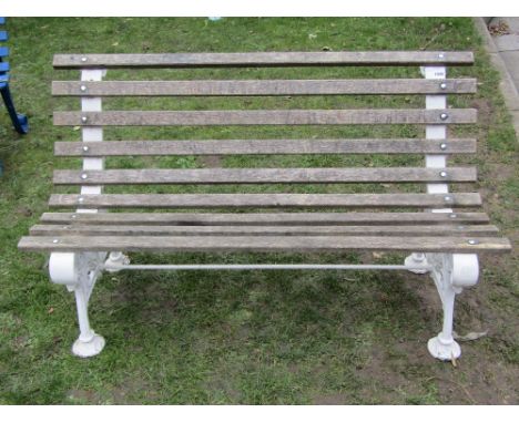 A two seat garden bench with weathered timber lathes, raised on a pair of decorative Victorian cast iron end supports, with s