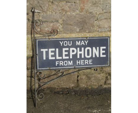 A vintage enamel sign, twin sided with white lettering on a navy blue ground 'You may telephone from here' set within a possi