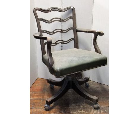 An Edwardian mahogany office chair with swivel base and scrolled arms, the back with pierced ladder back and anthemion mouldi