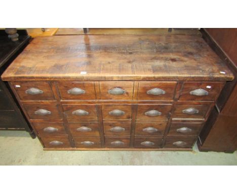 A vintage style pine cabinet presented as 20 small drawers, comprising 11 drawers surrounding two cupboards, 133cm wide