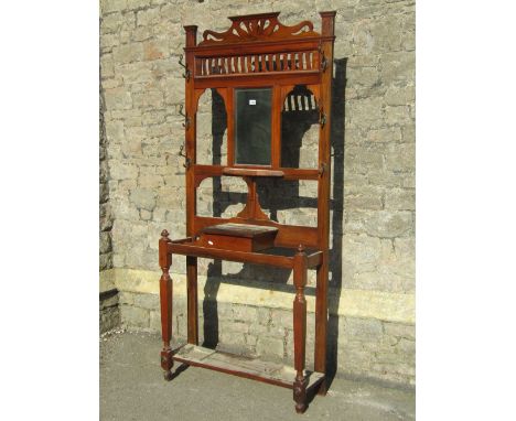 An Edwardian walnut hall stand of full height, the back incorporating a rectangular bevelled edge mirror plate flanked by coa