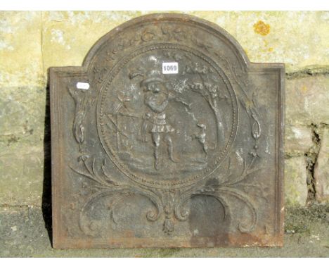 A small antique cast iron fire back of stepped arched form,  with raised relief detail of a male character playing a pipe alo