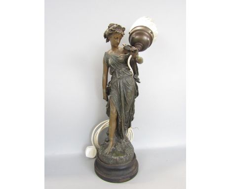 French cast spelter figural table lamp in the form of a robed maiden holding a glass flambeau finial, the stepped circular pl