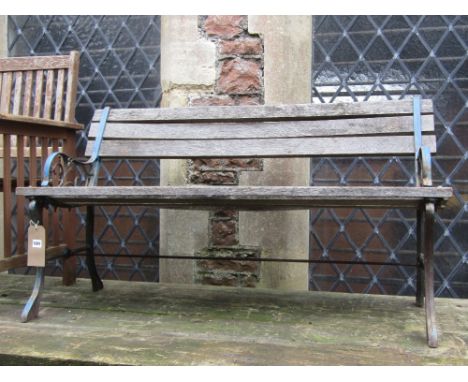 A two seat garden bench with weathered timber lathes, raised on decorative cast iron end supports, together with one other wi