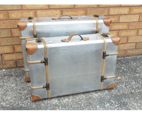 Two graduated vintage style metal suitcases with leather and wooden trim