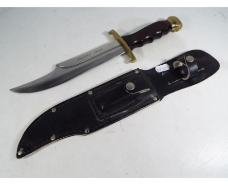 A classic Bowie knife with approx 21 cm blade. The blade is chrome plated and has a fuller running 2/3 of its length with "Cr