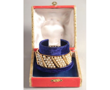 A GOOD YELLOW METAL AND SEED PEARL BANGLE, comprising nine panels of three rows of pearls.