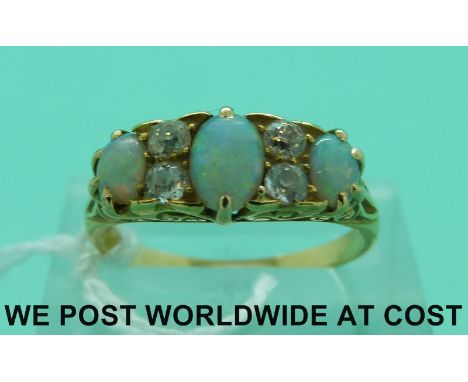 A Victorian/Edwardian yellow metal ring set with three opal cabochons and four old cut diamonds (size O)