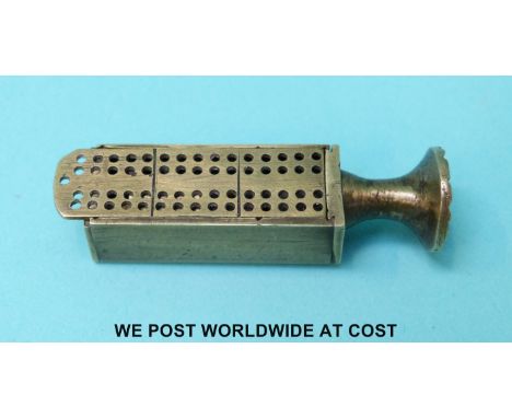 A novelty pipe tamper with slide out cribbage board lid, opening to reveal two miniature dice and a quantity of brass dominoe