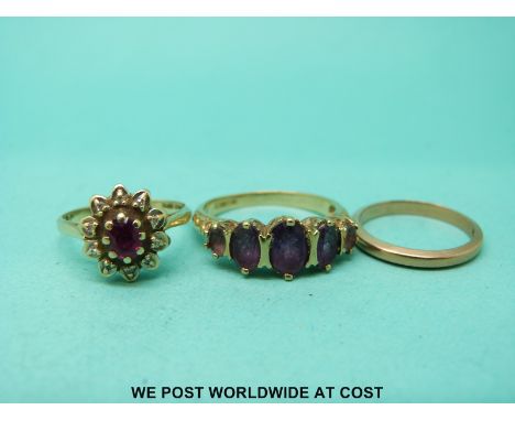 A 9ct gold ring set with a ruby surrounded by diamonds, a 9ct gold wedding band and a 9ct gold ring set with amethysts 