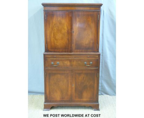 A mahogany reproduction drinks cabinet/tallboy having two cupboards over and two under with drawer and brushing slide or shel