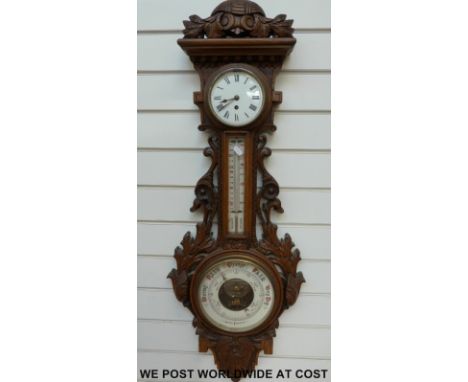 A circa 1900 ornately carved oak aneroid barometer/clock compendium, the enamelled dials having numerals and weather predicti