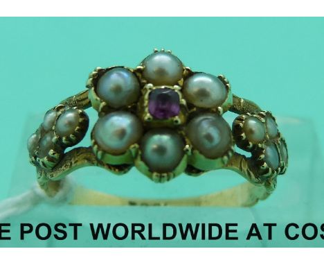 An 18ct gold ring set with a ruby surrounded by seed pearls in a cluster, with glass compartment verso (size K)