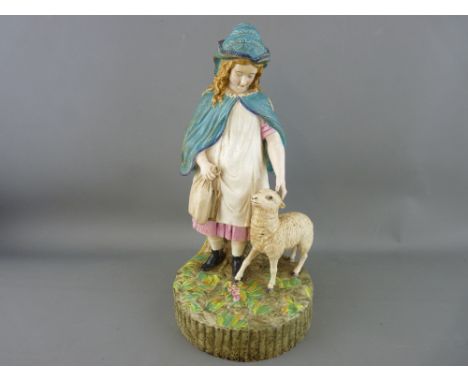 Victorian pottery figurine depicting a young girl in blue hooded cloak with a sheep at her feet, decorated in colourful ename