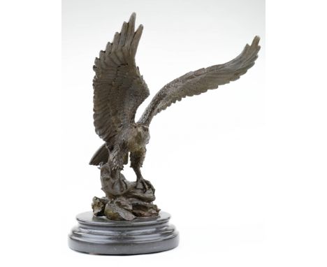 A stunning bronze cast eagle perched atop a log, standing 17 in. tall x 13 in. wide, with its wings spread. The statue stands
