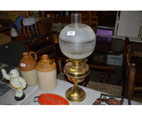 A brass oil lamp with glass chimney and shade