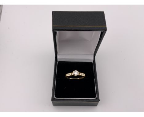 An 18ct gold 0.50ct solitaire diamond ring with channel set diamond shoulders. Size M. (Postage A)