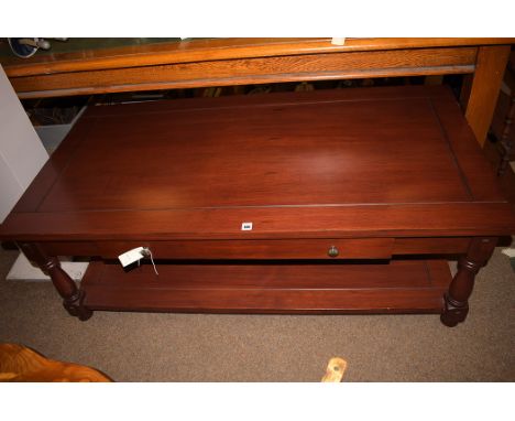 A stained wooden rectangular coffee table, with fitted central drawer and shelf below, raised on turned legs.