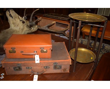 Two small brass benares circular trays; a vintage leather suitcase; and another small suitcase.
