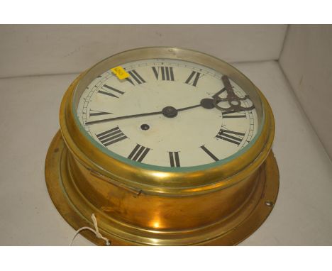 An early 20th Century circular brass ship clock with enamel roman dial.