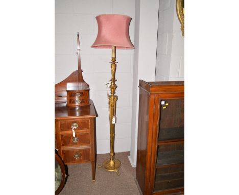 A mid 20th Century giltmetal standard lamp, decorated with ram's heads, terminating in claw feet, 68in. high with shade.