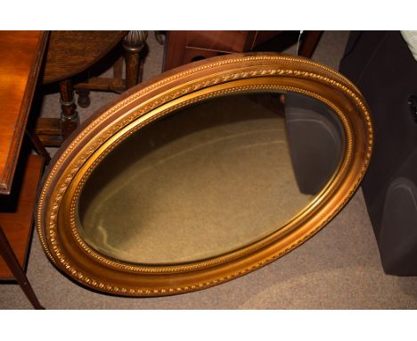 An oval gilt frame fitted a bevelled glass mirror, 36in. wide.