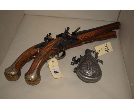 A pair of reproduction flint-lock pistols, stamped London to sides; and a pewter powder flask.  (3)