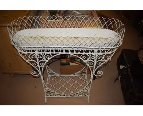 A painted brass planter on elaborate metal stand with shelf below.