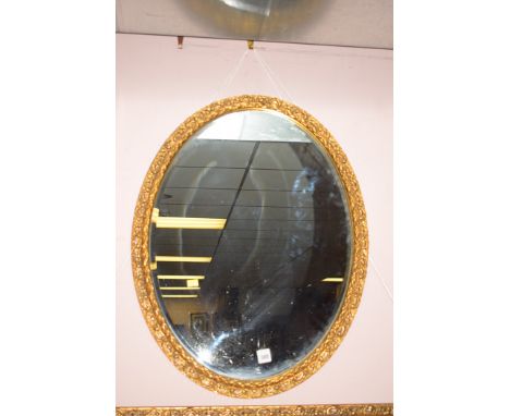 An oval gilded bevelled mirror, 27in high.