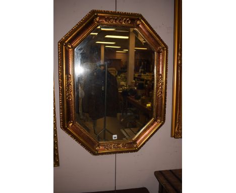 An modern octagonal bevelled wall mirror in gold painted frame.
