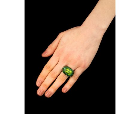 PERIDOT, TSAVORITE GARNET AND YELLOW SAPPHIRE RING, CIRCA 1995-2000Of bombé design, set with a rectangular cushion-shaped per
