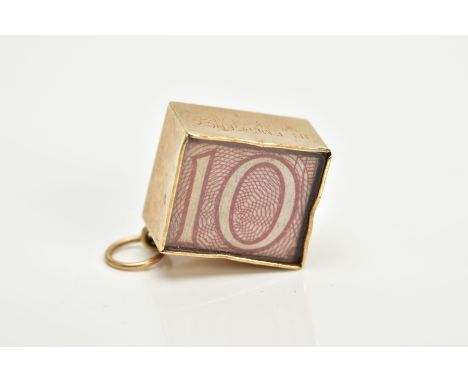 A 9CT GOLD CASED TEN SHILLING NOTE CHARM, the folded note within a plain polished square case and glass panel, stamped 'In Em