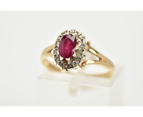 A 9CT GOLD RUBY AND DIAMOND CLUSTER RING, the raised cluster designed with a claw set oval cut ruby, within a single cut diam