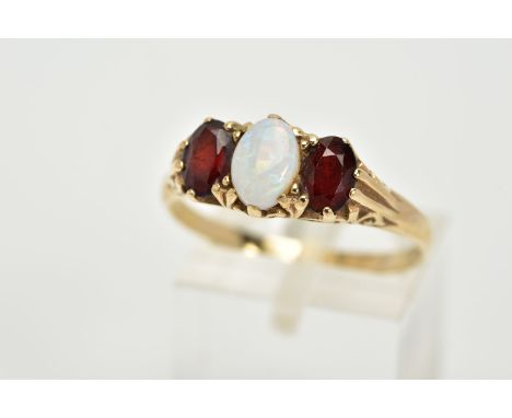 A 9CT GOLD THREE STONE RING, designed with a central oval cabochon opal, flanked with oval cut garnets, within an openwork sc