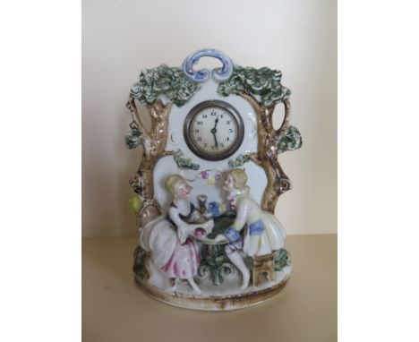 A china clock depicting couple at dining table with foliage 2 inch movement, condition report - working 
