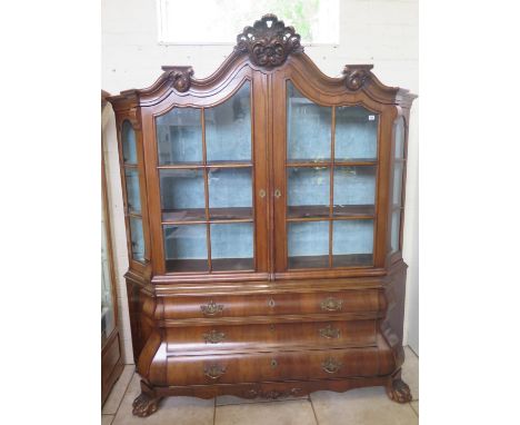 A 19th Century Dutch cabinet on chest with two shaped glazed doors above, three bombe shaped drawers on hairy claw and ball f