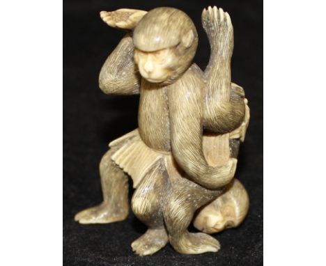A 19th Century Japanese Meiji Period carved ivory netsuke in the form of a pair of Sumo wrestling monkeys, each wearing a kes
