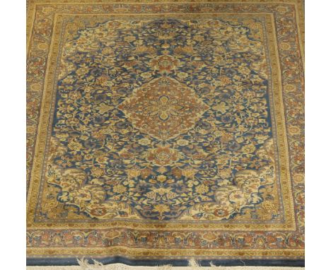 An Oriental carpet, the central medallion in cinnamon, pale gold, blue and cream, on a blue foliate decorated ground with fol