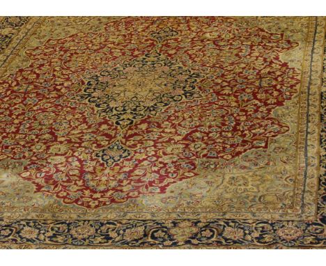 An Iranian Kashan carpet, the central floral medallion in dark blue, cream, pink, mustard and green on a red floral decorated