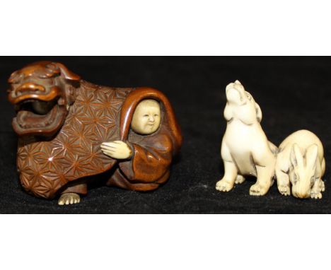 A 19th Century Japanese Meiji Period boxwood and carved ivory netsuke in the form of two figures in dragon costume, the drago