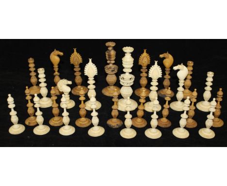 An early 20th Century carved ivory chess set of Indonesian style, one side natural, the other stained brown, natural side mis