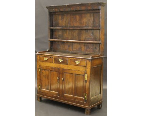 An 18th Century oak dresser with dentil cornice above iron cup hooks and two shelves, on a base of three short drawers with b