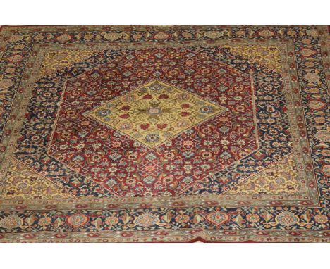 A Persian carpet, the central diamond shaped medallion in pale gold within floral and foliate decoration in burgundy, salmon,