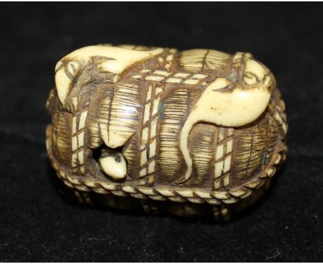 A 19th Century Japanese Meiji Period carved ivory netsuke in the form of a basket of rats, the cylindrical shaped basket with